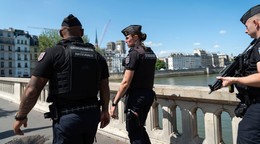 Policajti hliadkujú na moste cez rieku Seina v Paríži pred OH 2024.