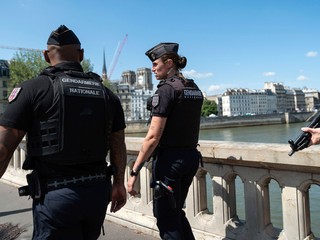 Policajti hliadkujú na moste cez rieku Seina v Paríži pred OH 2024.