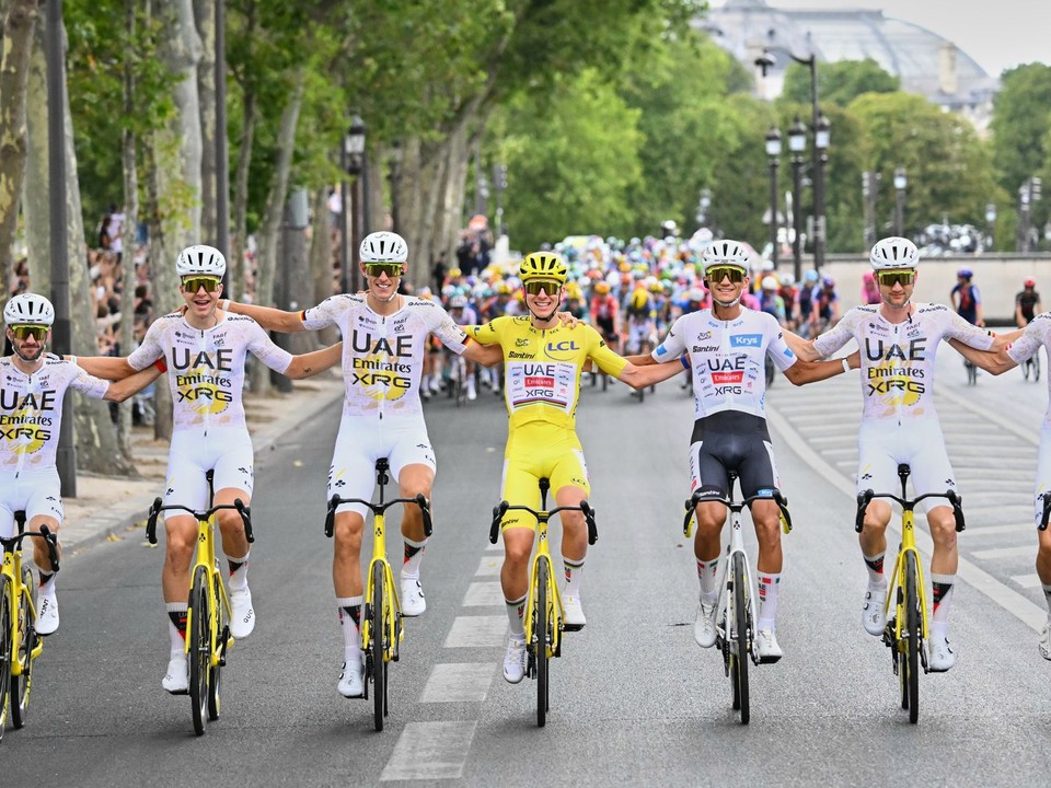 Slovinec Tadej Pogačar, oblečený v žltom drese lídra celkového poradia, oslavuje so svojimi tímovými kolegami z UAE Team Emirates.