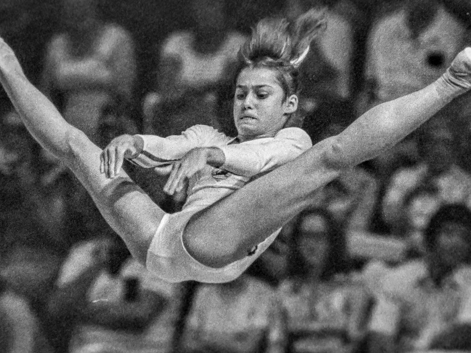 Nadia Comaneciová na bradlách na OH 1976 v Montreale. Mladú rumunskú gymnastku zachytil objektívom známy slovenský športový fotograf Peter Pospíšil a za fotografiu získal tretie miesto v celosvetovej súťaži Medzinárodnej asociácie športovej tlače (AIPS) o najlepšiu športovú snímku roka 1976.