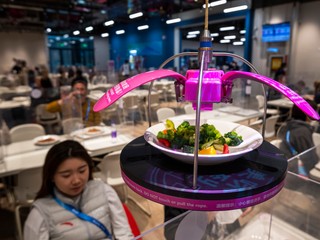 Špeciálny dopravný systém podáva jedlo v jedálni v hlavnom tlačovom centre.