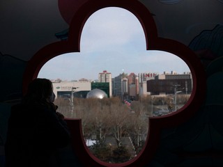 Žena sa pozerá z okna na Olympijský park v hlavnom tlačovom stredisku v Pekingu.