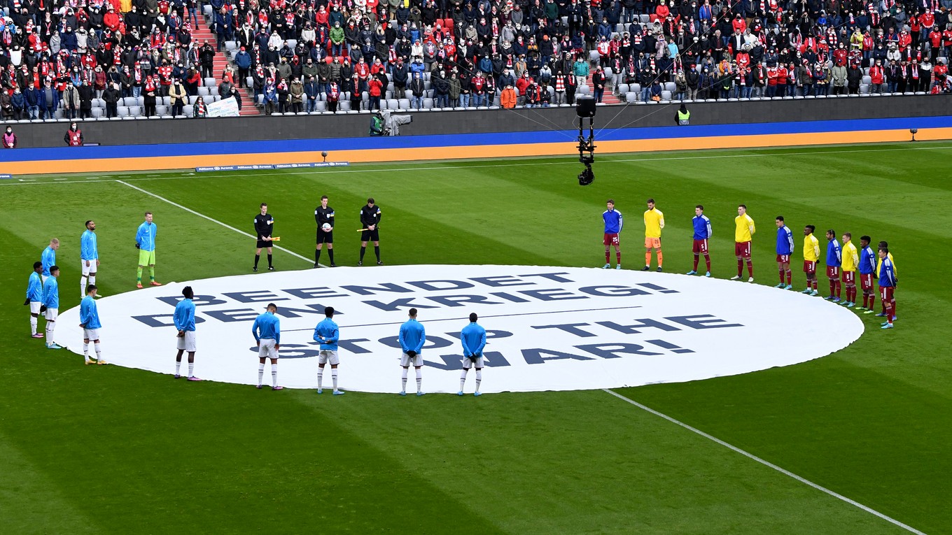 Hráči Bayer Leverkusen a Bayern Mníchov stoja počas minúty ticha pri transparente s nápisom "Zastavte vojnu" pred zápasom Bundesligy.