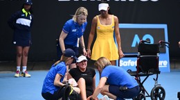 Priscilla Honová z Austrálie (vpravo) sleduje, ako jej súperke Marine Stakusicovej z Kanady poskytujú zdravotné ošetrenie počas ich zápasu.