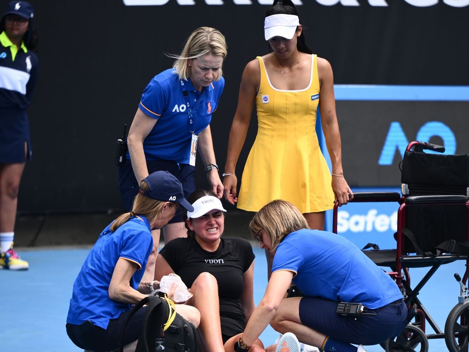 Priscilla Honová z Austrálie (vpravo) sleduje, ako jej súperke Marine Stakusicovej z Kanady poskytujú zdravotné ošetrenie počas ich zápasu.