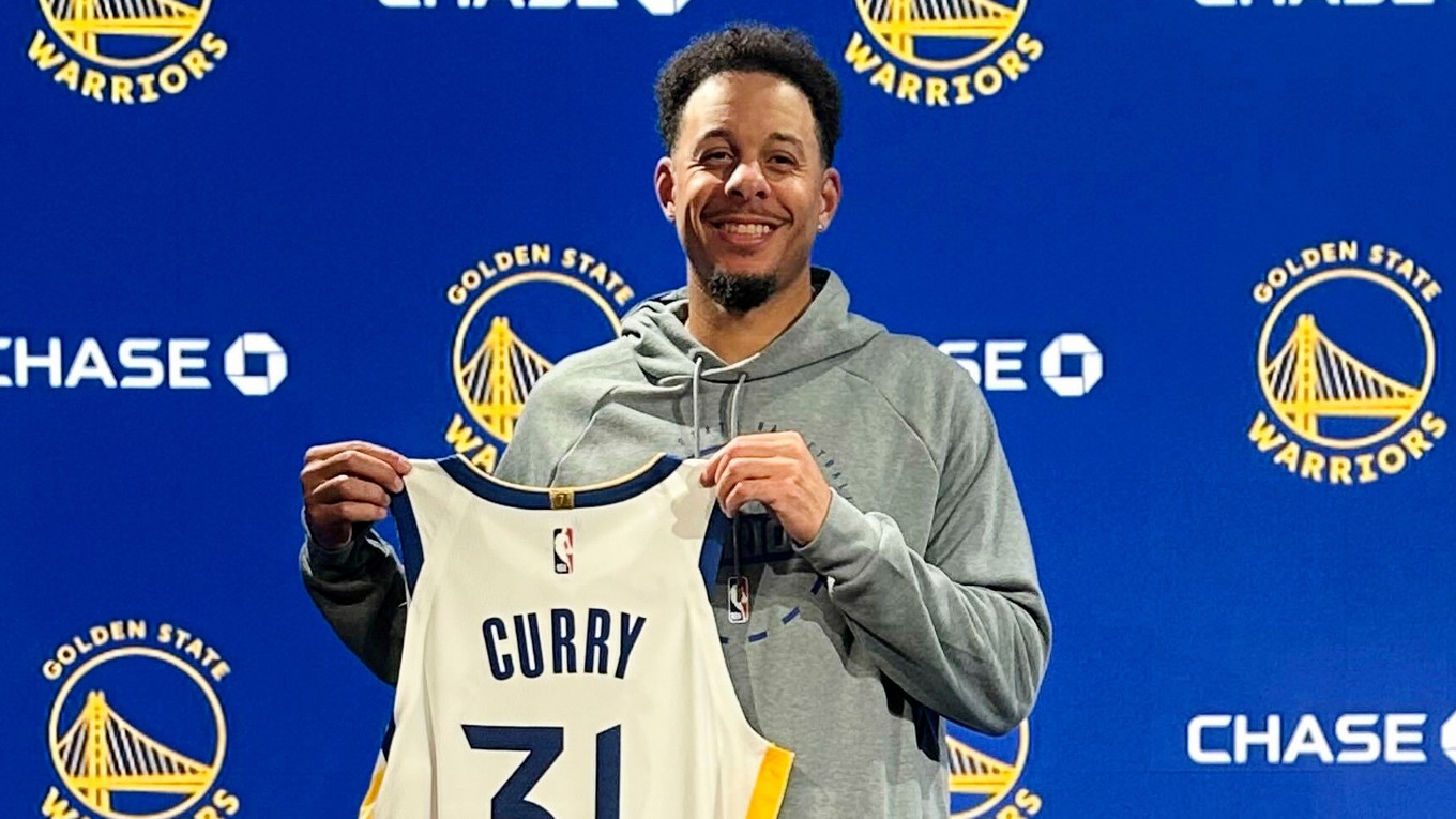 Seth Curry pózuje s dresom Golden State Warriors.