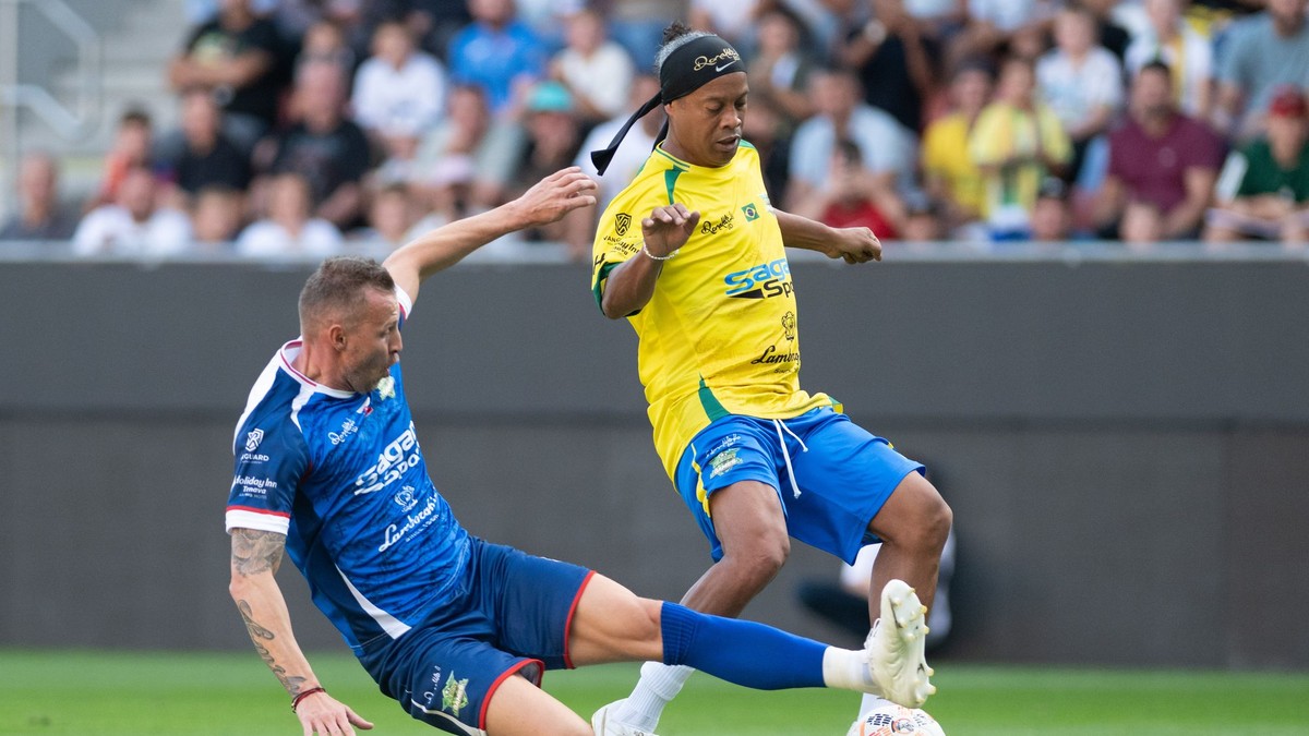 Na snímke vpravo bývalý brazílsky futbalista Ronaldinho a bývalý slovenský futbalista Ján Ďurica bojujú o loptu.