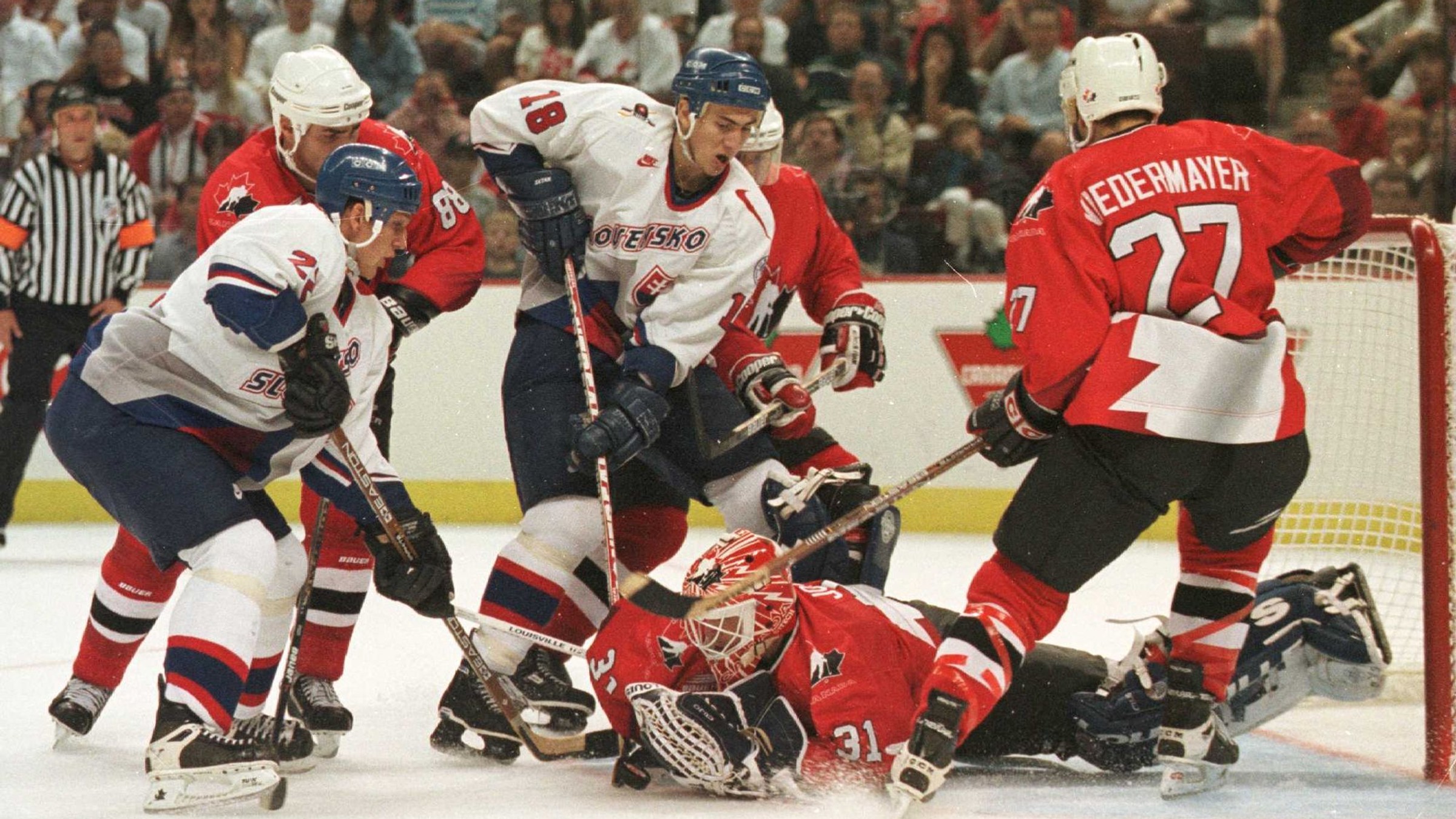 Brankár Kanady Curtis Joseph chytá puk pred Miroslavom Šatanom a Richardom Zedníkom v zápase Slovensko - Kanada na Svetovom pohári v hokeji 1996. 