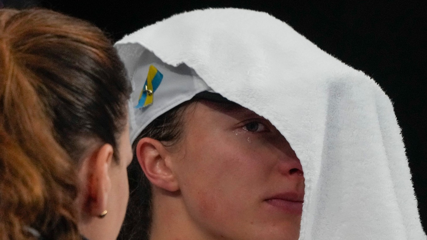 Poľská tenistka Iga Swiateková si zakrýva tvár uterákom. 