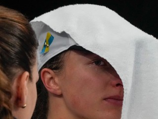 Poľská tenistka Iga Swiateková si zakrýva tvár uterákom. 