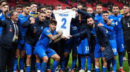 Grécki futbalisti držia dres Georga Baldocka. 