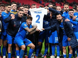 Grécki futbalisti držia dres Georga Baldocka. 