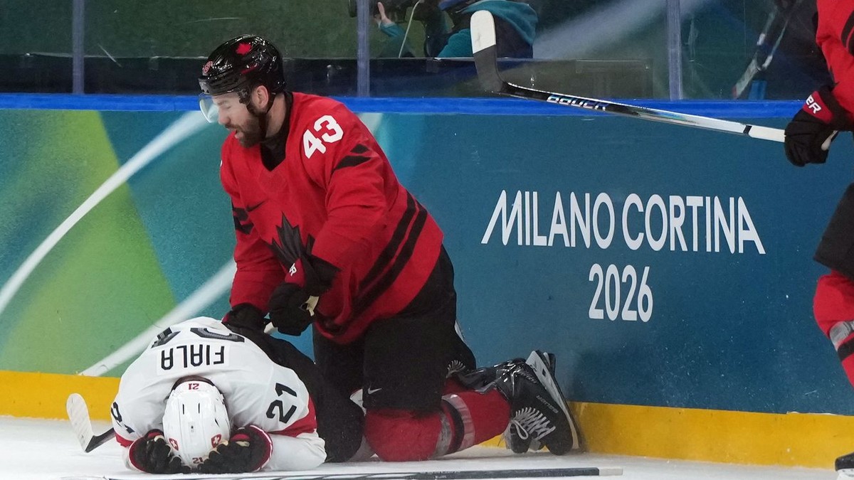 Zranený švajčiarsky hráč Kevin Fiala (vľavo) leží na ľade po zákroku Kanaďana Toma Wilsona.