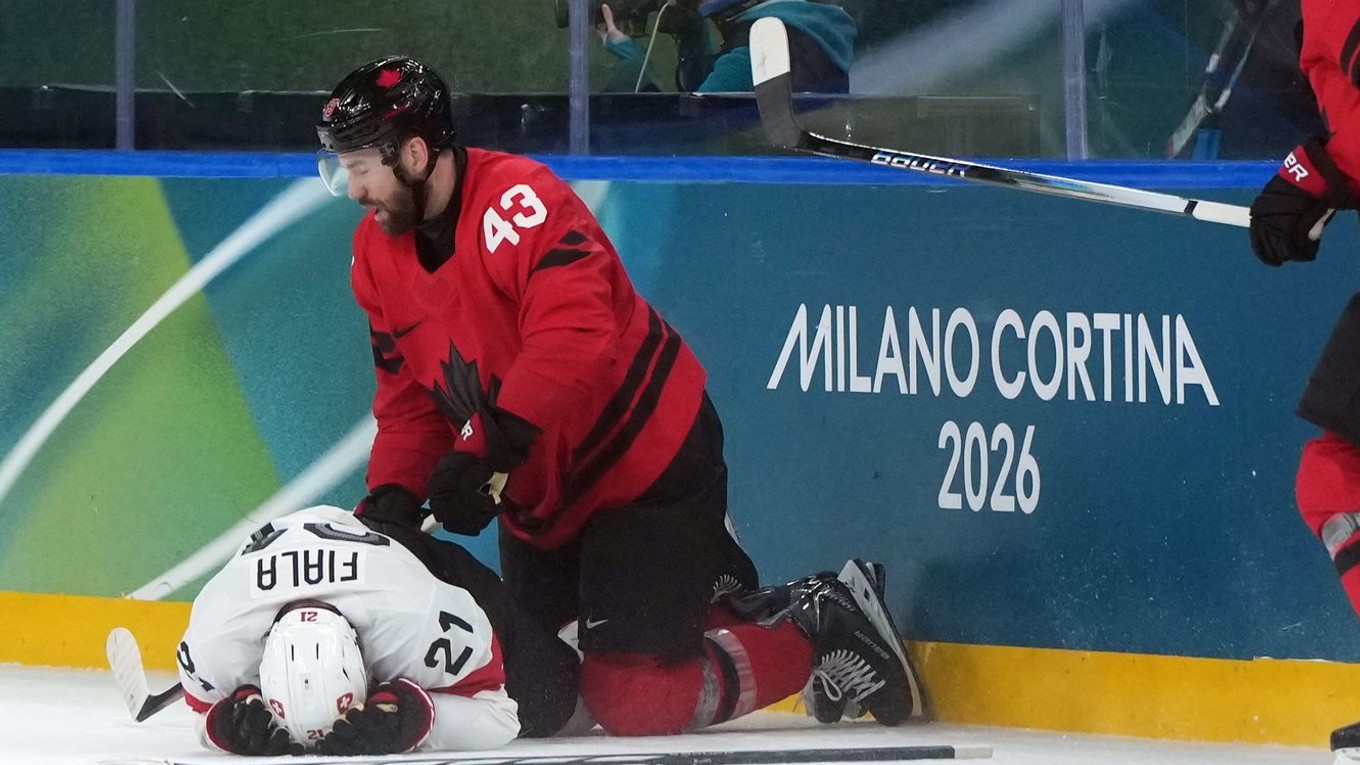 Zranený švajčiarsky hráč Kevin Fiala (vľavo) leží na ľade po zákroku Kanaďana Toma Wilsona.