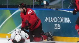 Zranený švajčiarsky hráč Kevin Fiala (vľavo) leží na ľade po zákroku Kanaďana Toma Wilsona.