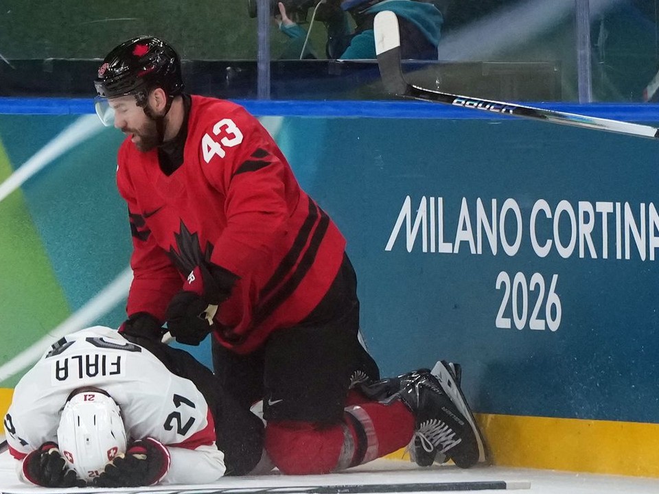 Zranený švajčiarsky hráč Kevin Fiala (vľavo) leží na ľade po zákroku Kanaďana Toma Wilsona.