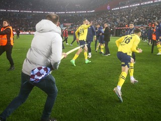 Fanúšik Trabzonsporu uteká s rohovou zástavou k hráčovi Fenerbahce Istanbul Mertovi Müldürovi.