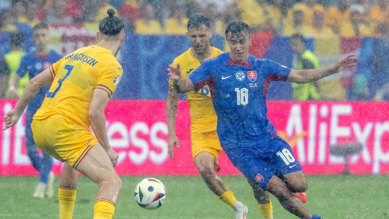 Dávid Strelec, Alexandru Cicaldau a Radu Dragusin  v hustom daždi počas zápasu základnej E-skupiny Slovensko - Rumunsko na ME 2024 vo futbale 