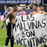 Argentínski futbalisti s bannerom s nápisom: "Falklandy sú Argentína."