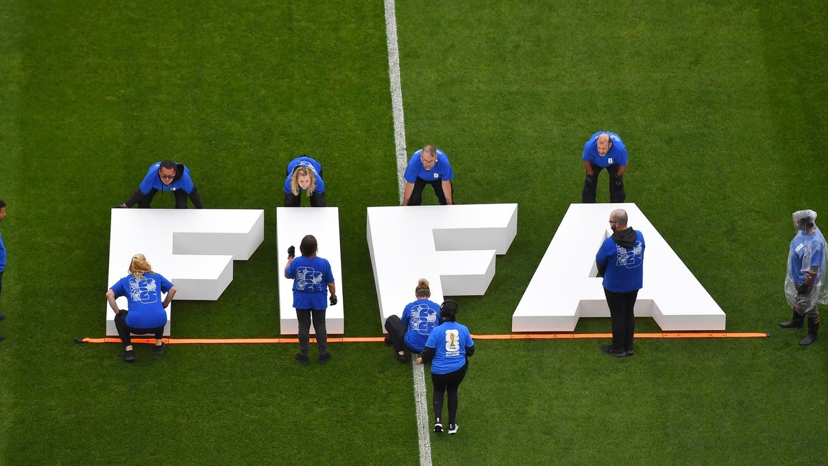 Na snímke pracovníci umiestňujú na trávnik nápis Medzinárodnej futbalovej federácie (FIFA).
