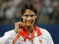 Španielsky tenista Rafael Nadal sa zahryzáva do zlatej medaily  na OH 2008 v Pekingu 2008.