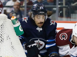 Mathieu Perreault (v strede) z Winnipegu obieha s pukom bránku bránený Alexandrom Kerfootom z Colorada.