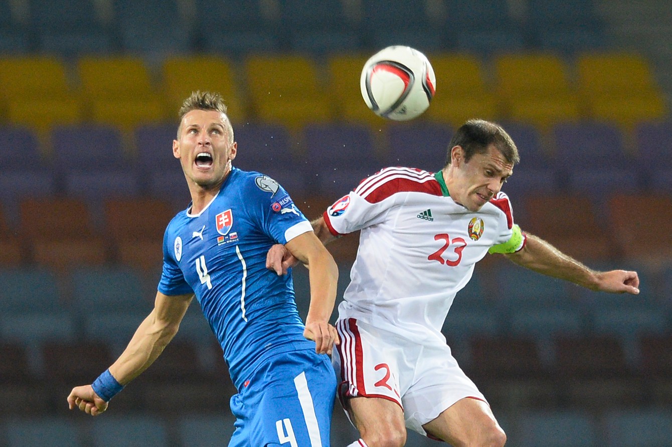 Ján Ďurica (vľavo) v súboji s Timofejom Kalačevom v kvalifikačnom zápase o postup na ME 2016 Bielorusko - Slovensko 1:3 (Borisov, 12. októbra 2014).