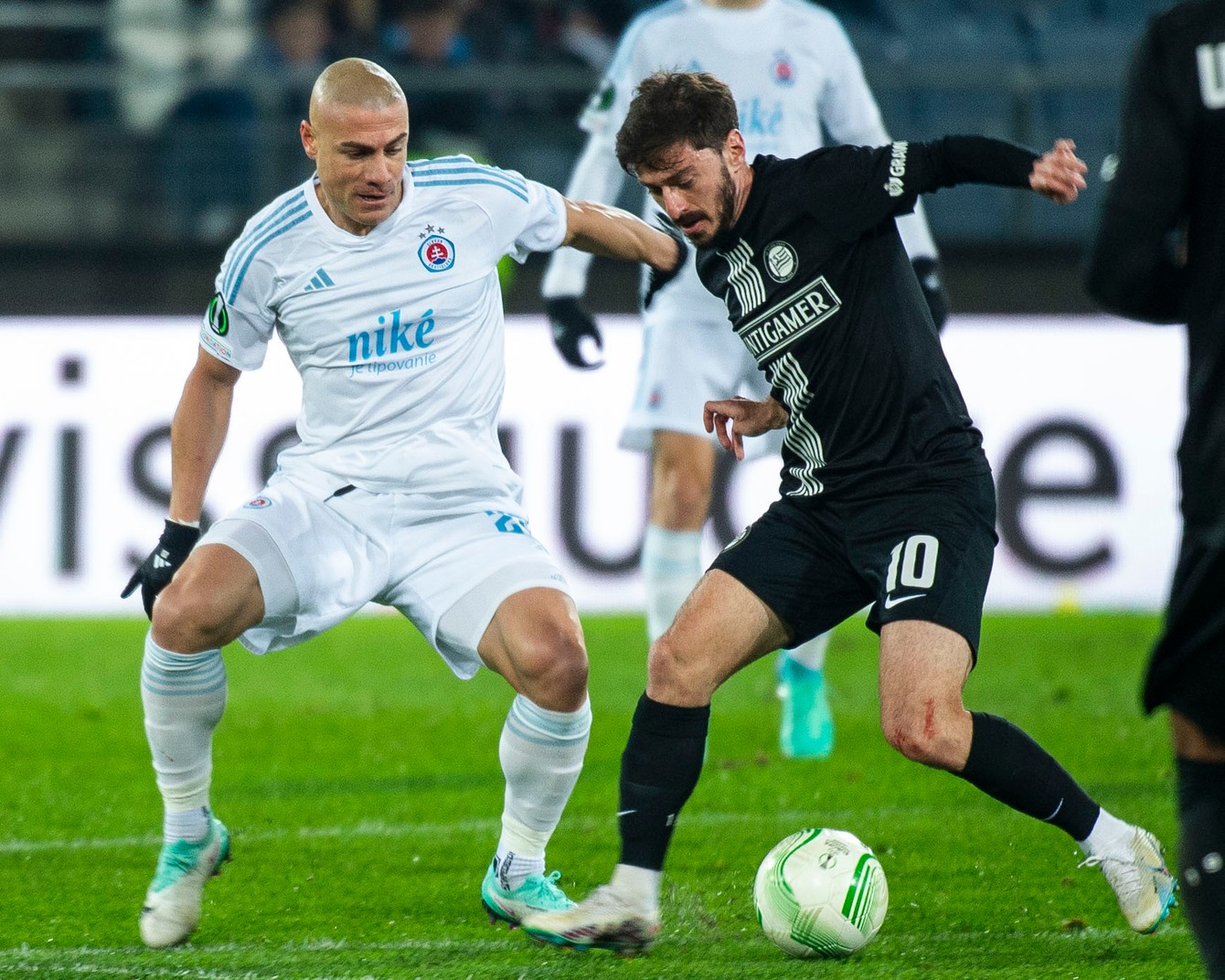Vľavo Džaba Kankava (Slovan) a Otar Kiteišvili (Graz) bojujú o loptu v prvom zápase play off o osemfinále Európskej konferenčnej ligy (EKL) vo futbale SK Sturm Graz - ŠK Slovan Bratislava v Grazi (15.2.2024).