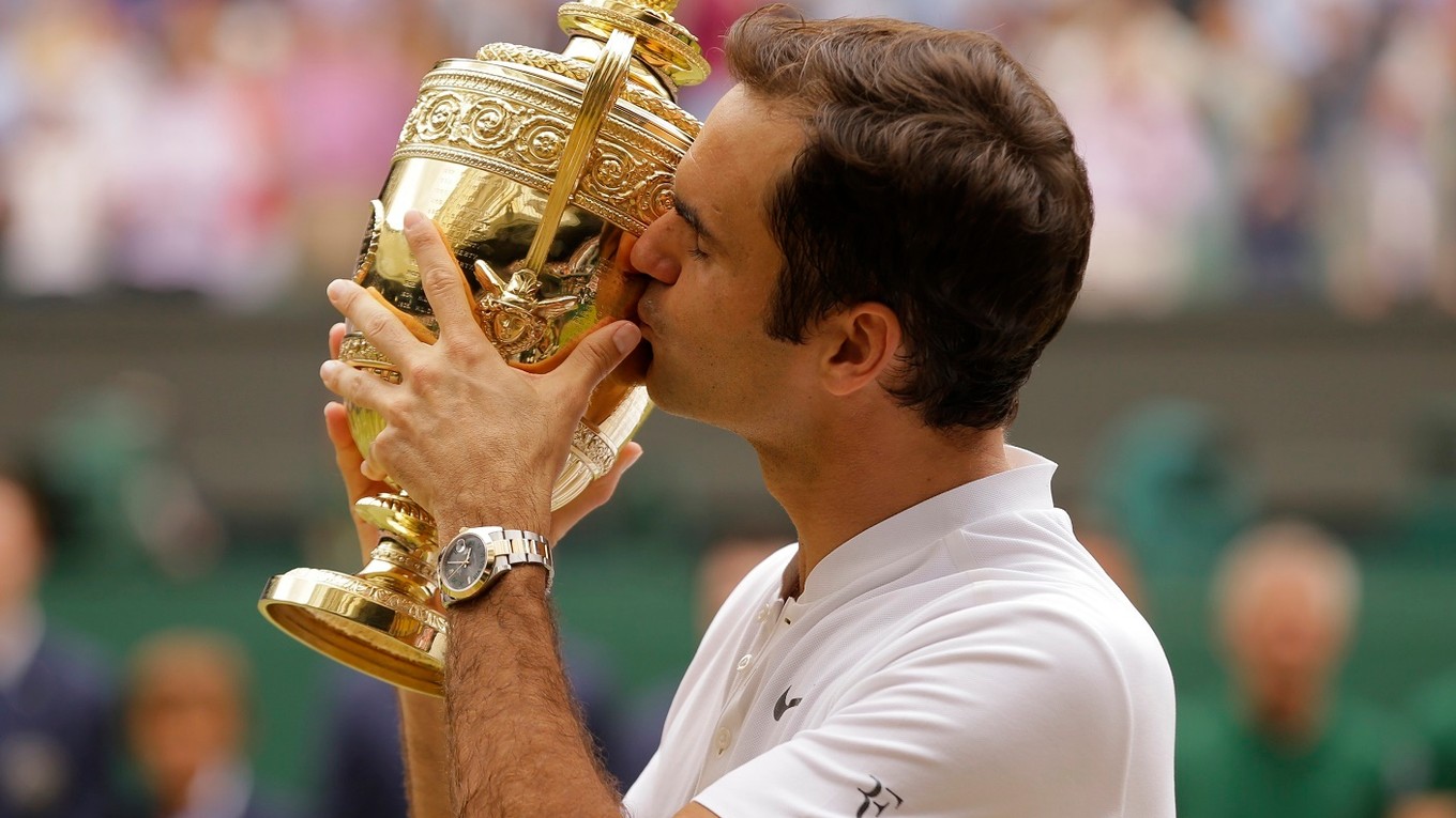 Roger Federer bozkáva trofej pre víťaza Wimbledonu.
