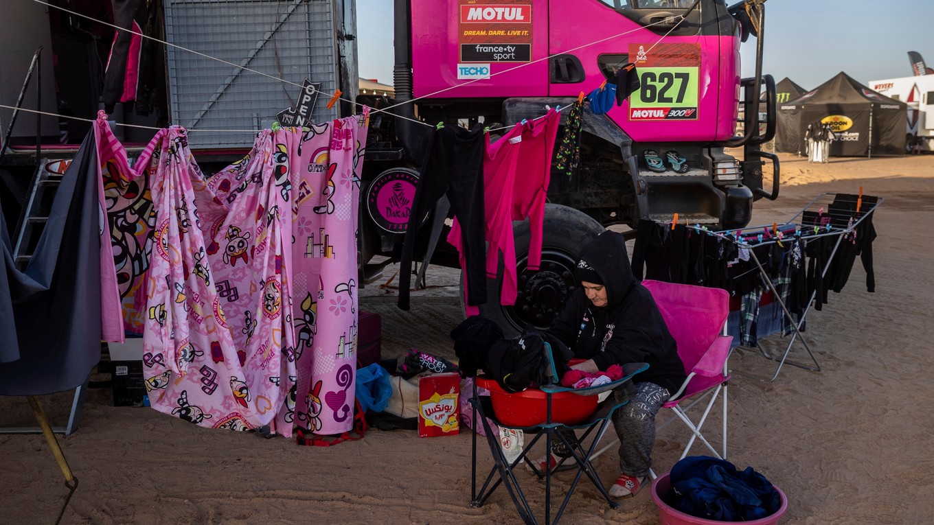 Žena perie a vešia prádlo vedľa kamióna počas voľného dňa na Rely Dakar. 