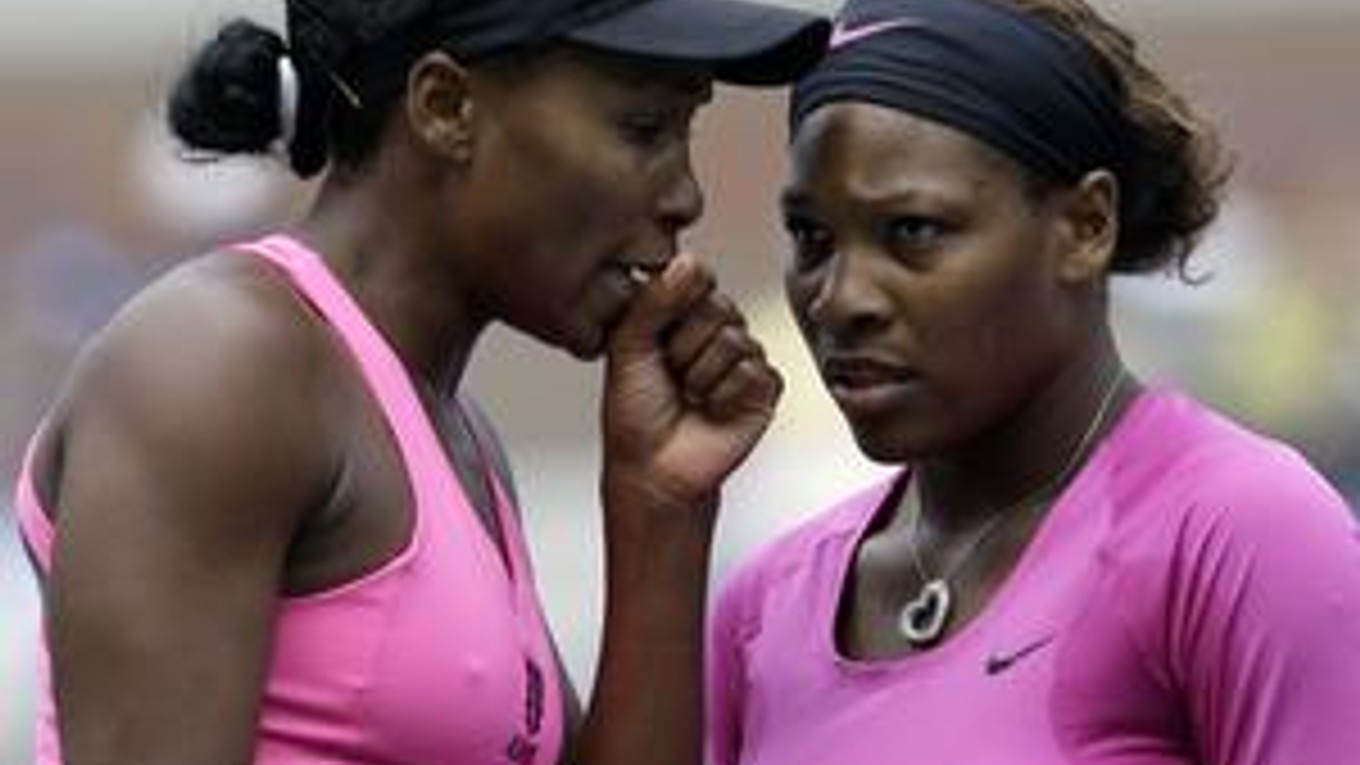 Americká tenistka Venus Williamsová (vľavo) si vymieňa pokyny so sestrou Serenou počas semifinále štvorhry žien proti ruskému páru Alise Klejbanovovej a Jekaterine Makarovej.