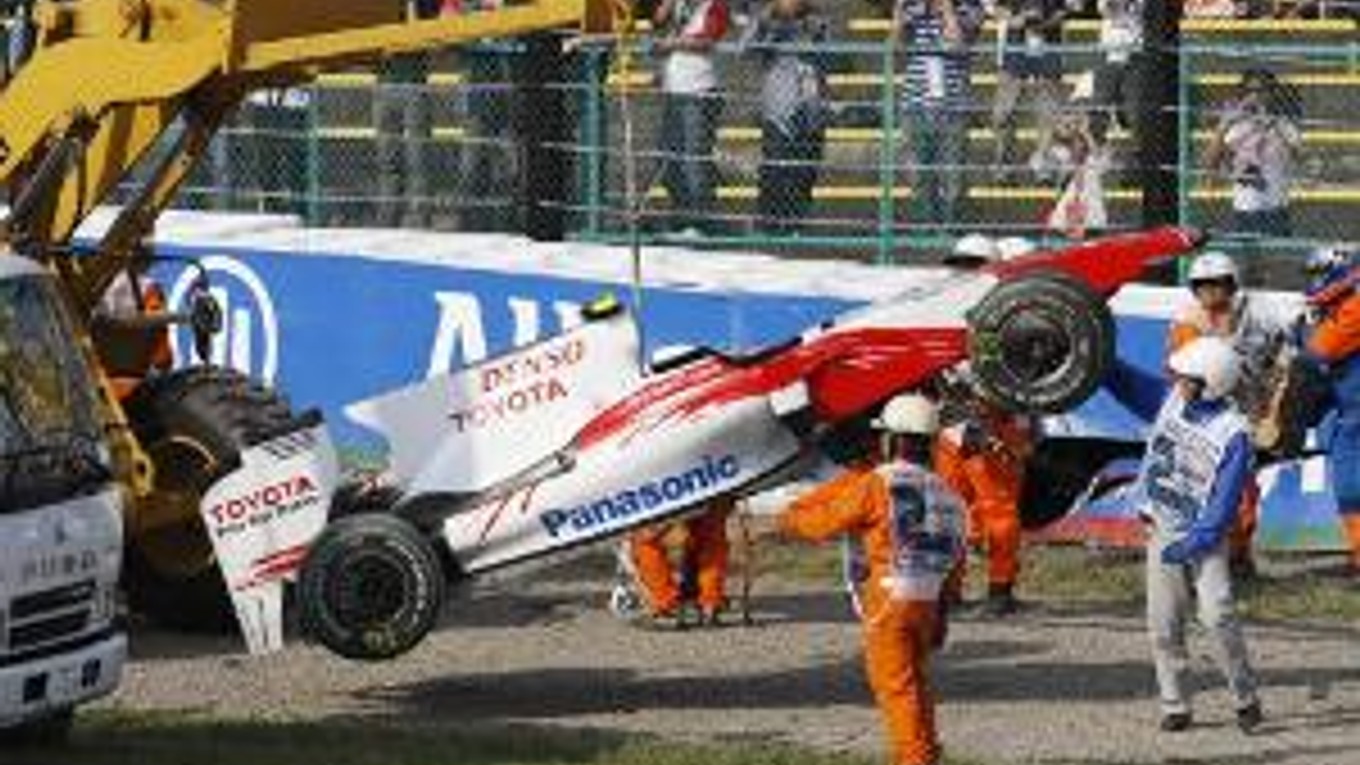 Usporiadatelia odnášajú havarovaný monopost Tima Glocka.