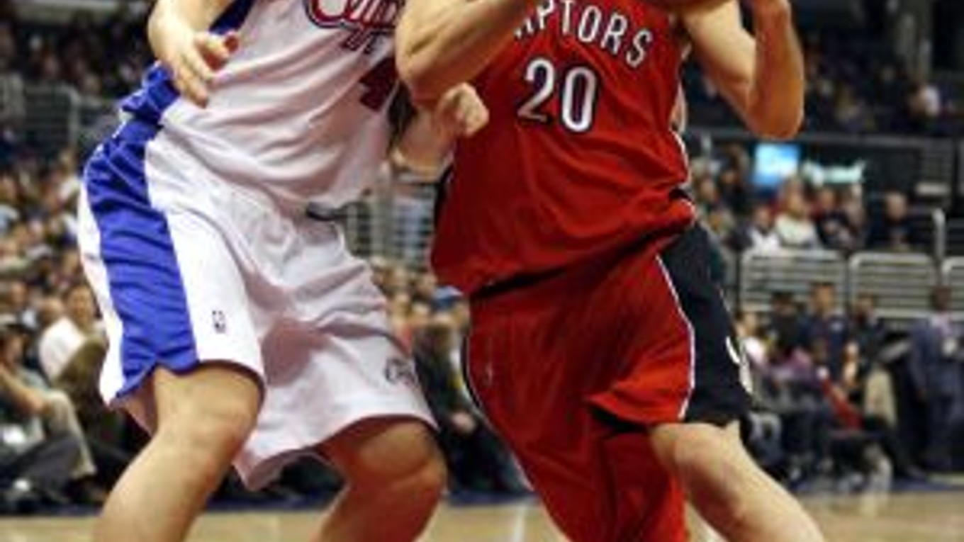 Carlos Delfino z Toronta (v červenom) sa pokúša zakončiť cez hráča Los Angeles Clippers Paula Davisa.