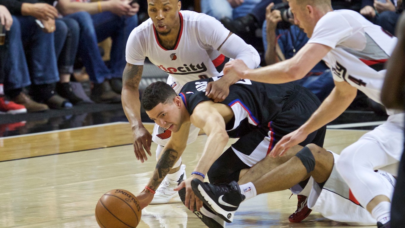 Hráč tímu LA Clippers J.J. Redick (v strede) sa naťahuje za loptou. Z oboch strán pribiehajú súperi z tímu Portlandu. 