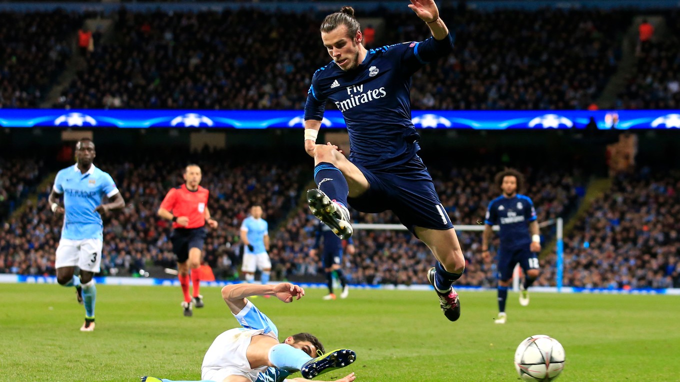 Jesus Navas (na zemi) z Manchestru City vypichuje loptu Garethovi Baleovi.