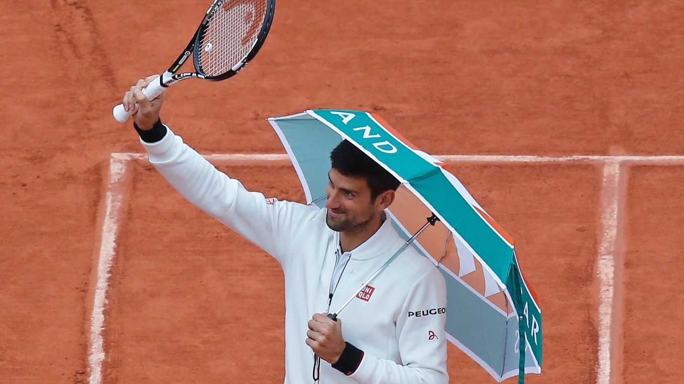 Aj takto to dnes vyzeralo v Paríži. Novak Djokovič si zobral od jedného z divákov v hľadisku dáždnik a pozdravil publikum s raketou v ruke.