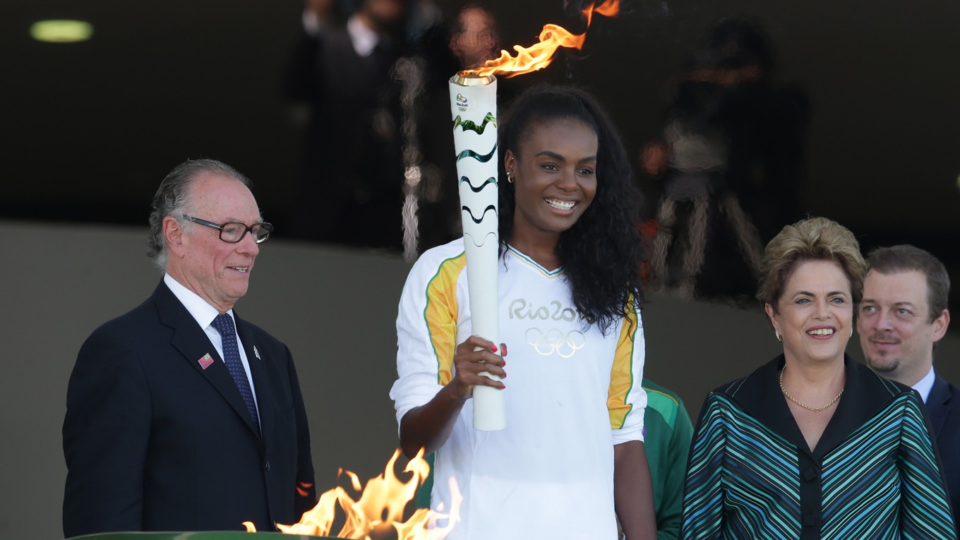 Brazílska volejbalistka Fabiana Claudinová (uprostred) drží horiacu olympijskú pochodeň.
