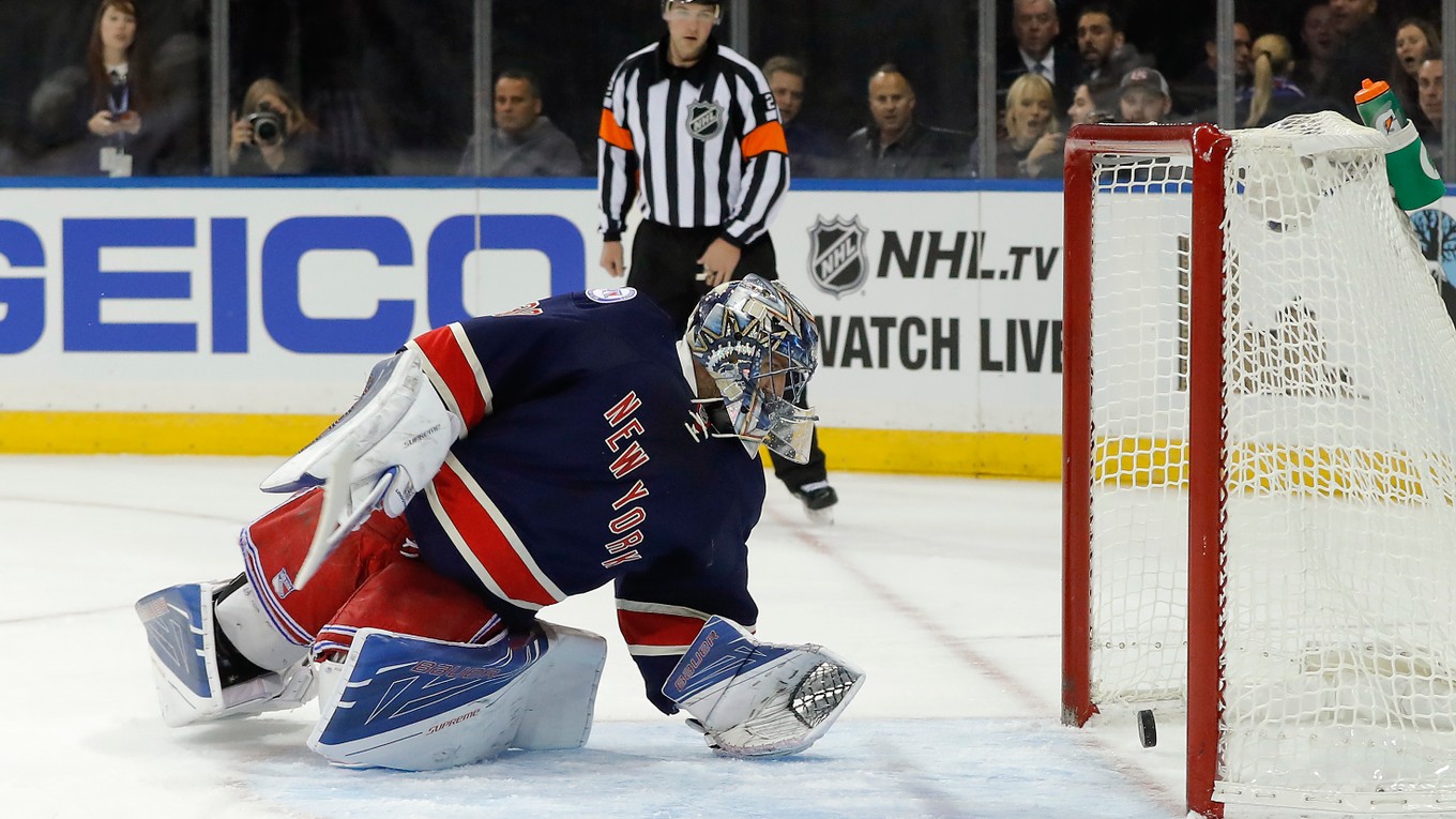 Brankár New Yorku Rangers Henrik Lundqvist vyťahuje zo svojej siete puk po rýchlom góle Bostonu Bruins.