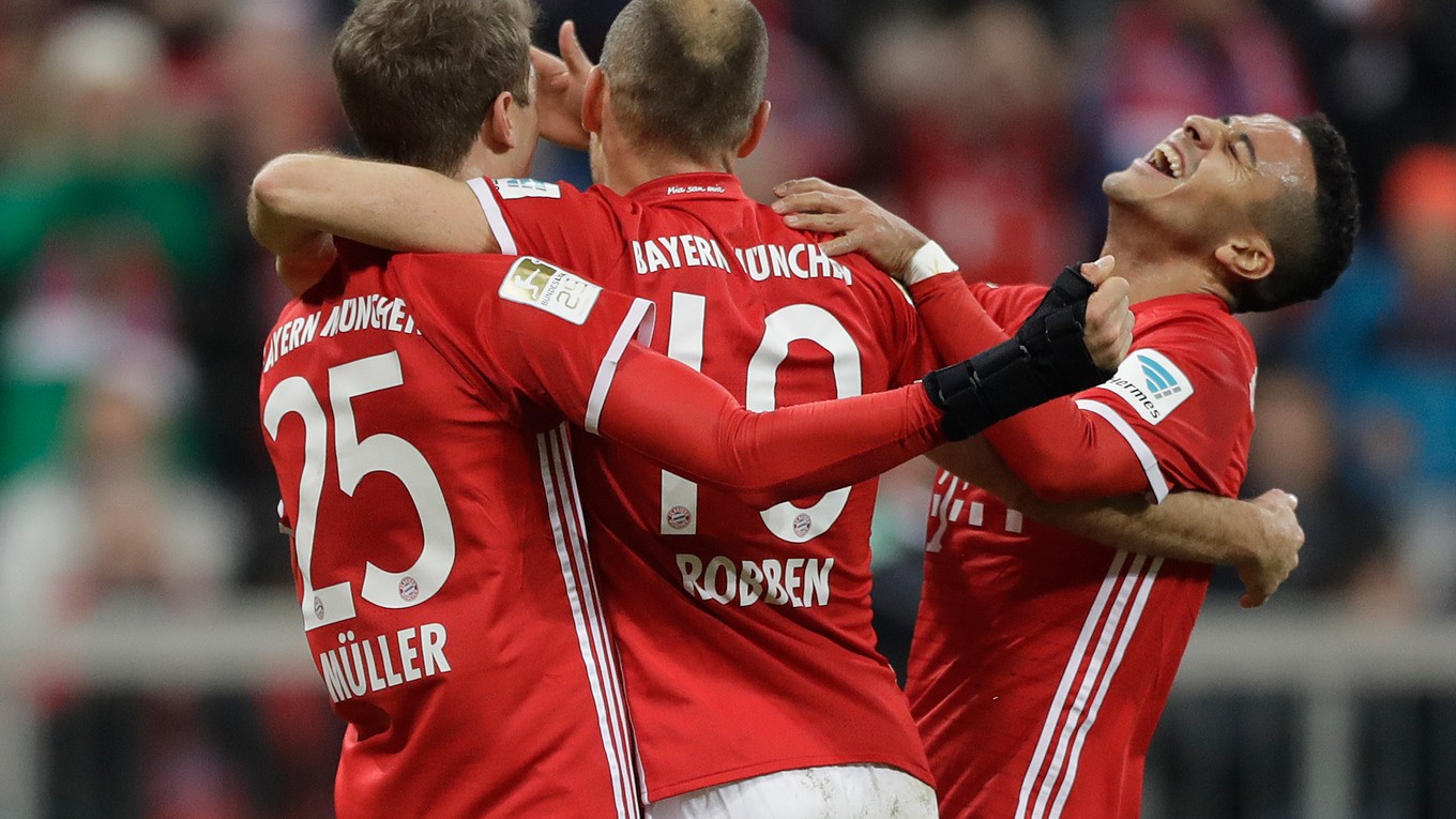 Thomas Mueller (vľavo) oslavuje so spoluhráčmi Arjenom Robbenom (uprostred)a Thiago gól do siete Wolfsburgu.