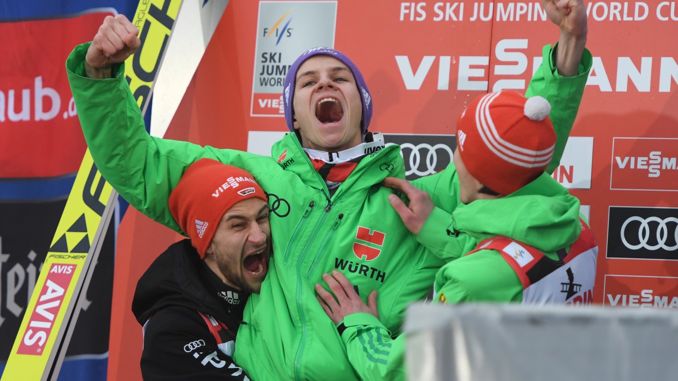 Kolegovia z nemeckého tímu Markus Eisenbichler (vľavo) a Richard Freitag (vpravo) oslavujú s Andreasom Wellingerom jeho triumf.