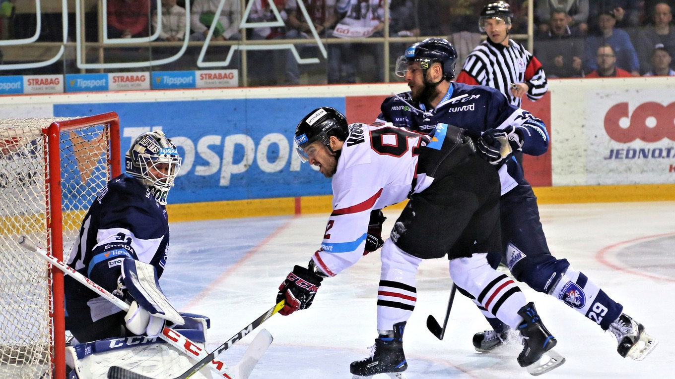 Brock Higgs (v strede v bielom) z Banskej Bystrice sa pokúša pretlačiť puk za chrbát brankára Mathieuho Corbeila.