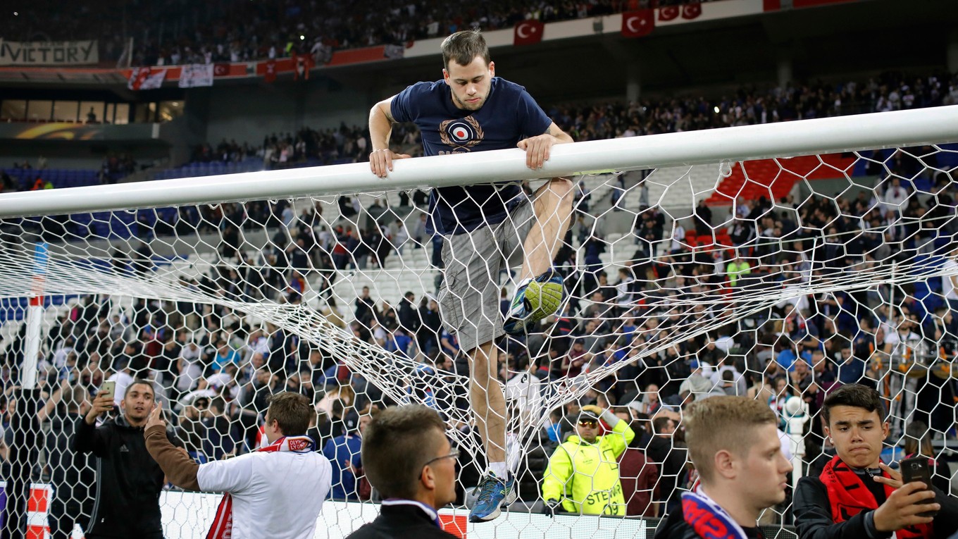 Fanúšik lezie na bránkovú konštrukciu potom, ako diváci vtrhli na trávnik štadióna.