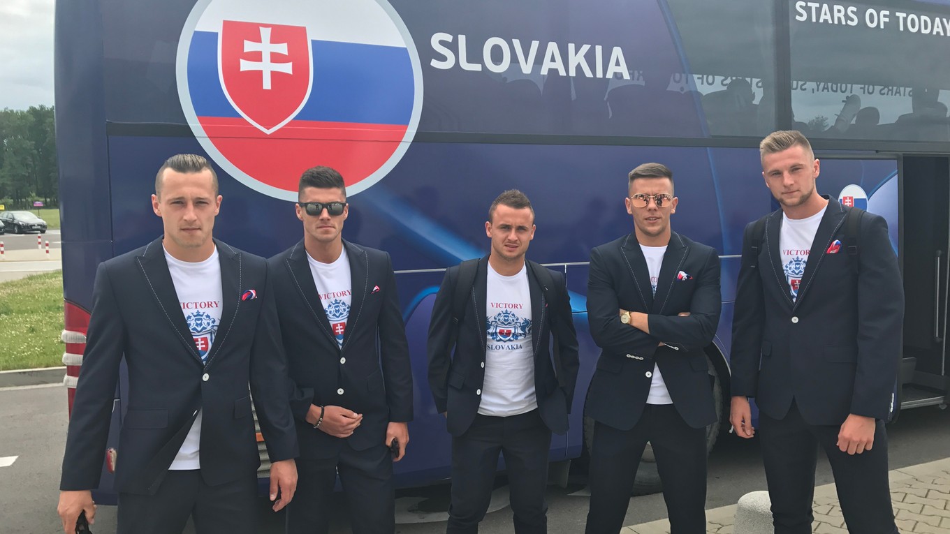 Slovenskí futbalisti pózujú pred autobusom, na ktorom bol zobrazený slovenský znak bez trojvršia.