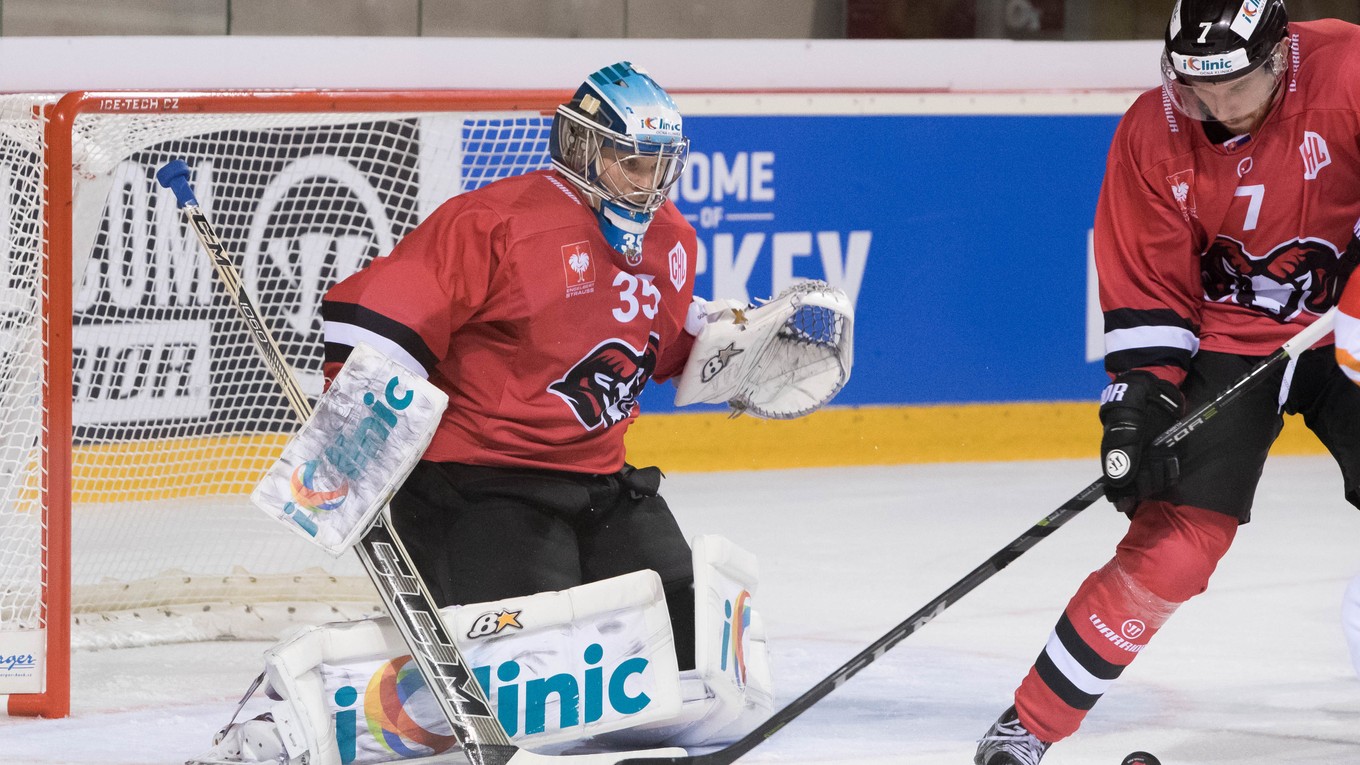 Obranca Banskej Bystrice Branislav Kubka odpaľuje puk pred spoluhráčom - brankárom Teemuom Lassilom.