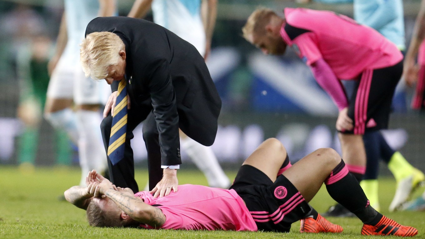 Tréner Škótov Gordon Strachan utešuje svojich zverencov po remíze v Slovinsku.