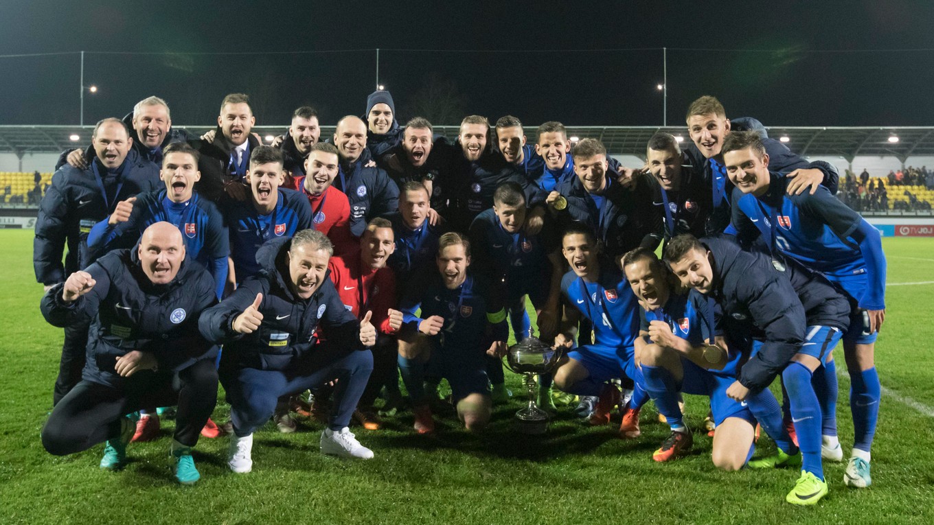 Slovenskí futbalisti sa spolu s realizačným tímom radujú z trofeje.
