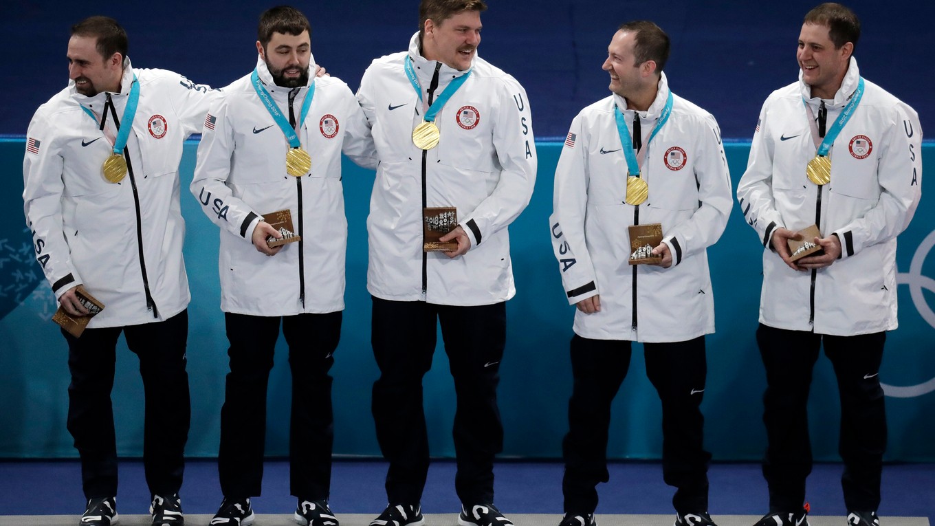 Americkí reprezentanti v curlingu zľava Joe Polo, John Landsteiner, Matt Hamilton, Tyler George a John Shuster oslavujú na pódiu víťazstvo a zisk zlatej medaily.