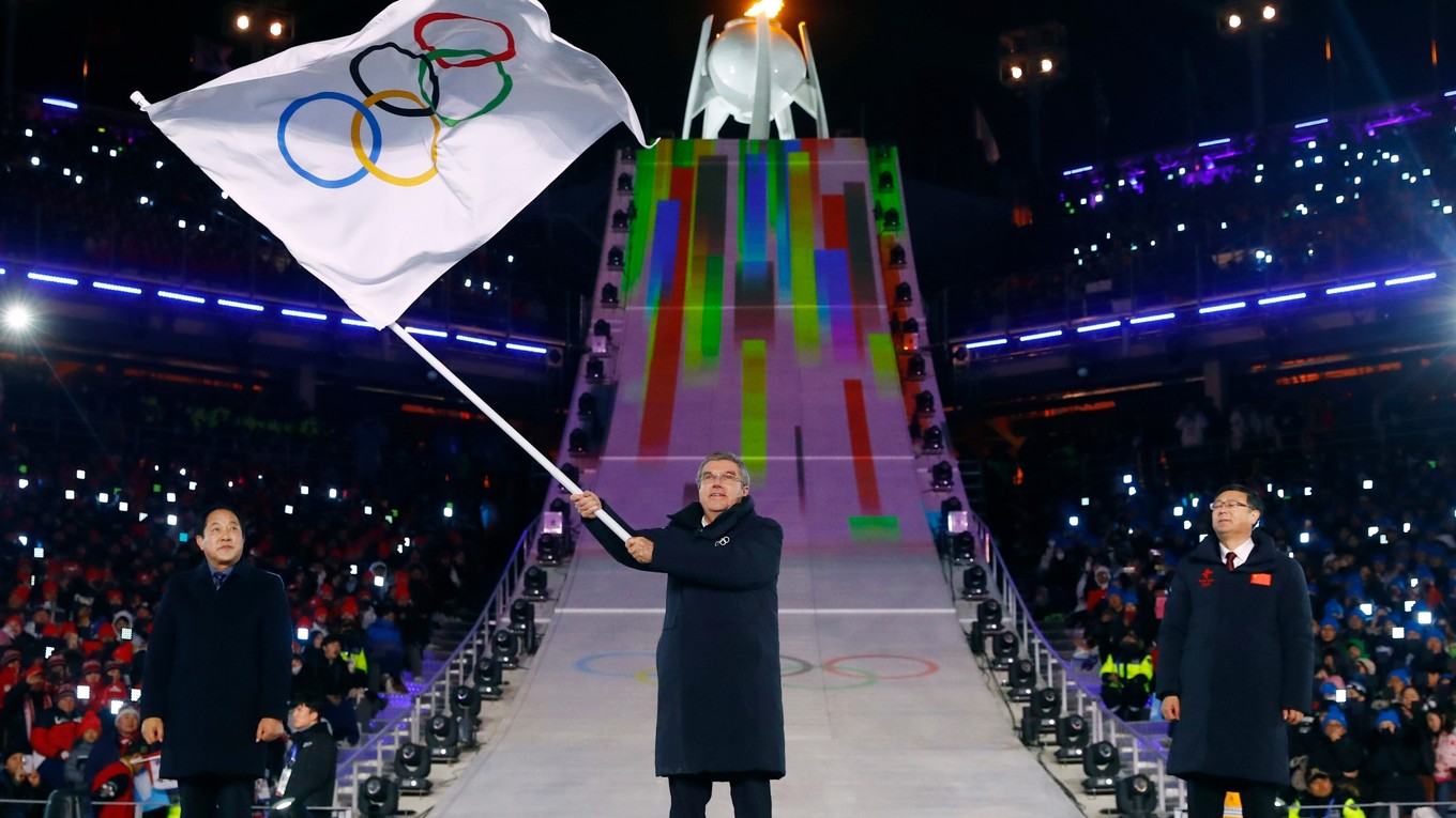 Prezident Medzinárodného olympijského výboru (MOV) Thomas Bach (uprostred) máva olympijskou zástavou počas záverečného ceremoniálu na ZOH 2018.