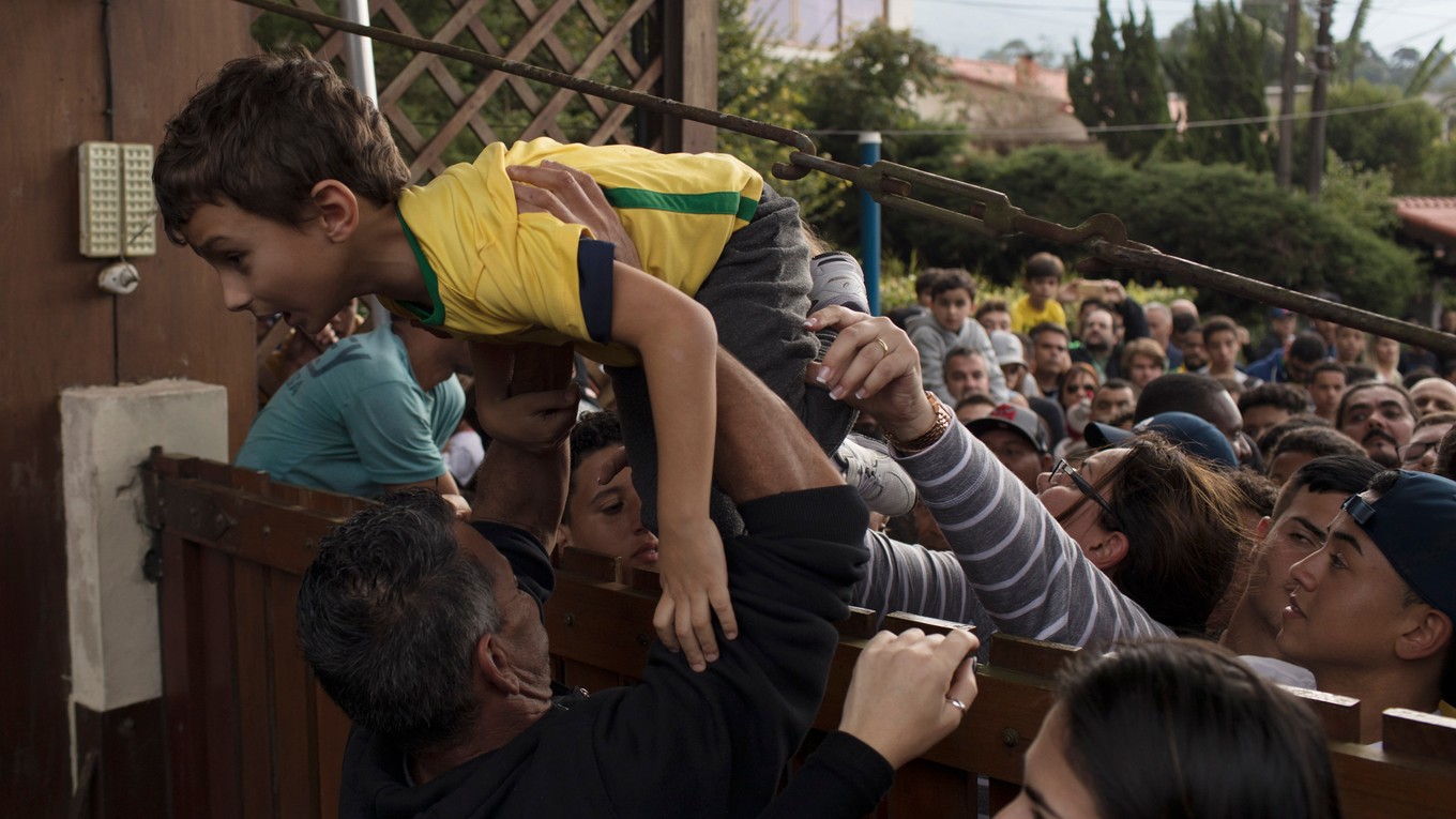Mldý  brazílsky fanúšik sa tlačí cez bariéru na tréning reprezentantov.
