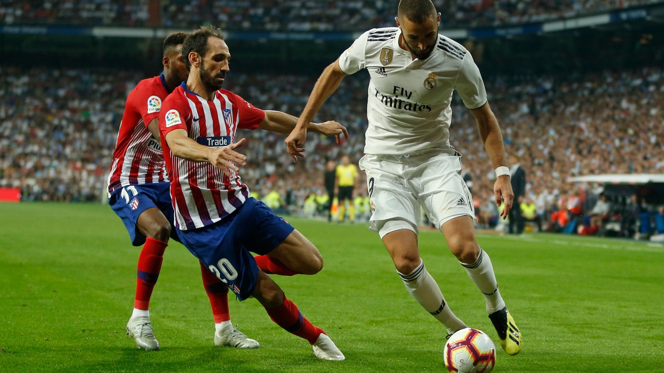 Karim Benzema (vpravo) kontroluje loptu pred obrancami Atletica Madrid. 